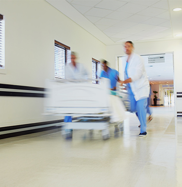 I chirurghi corrono con il letto di un paziente lungo un corridoio dell'ospedale.