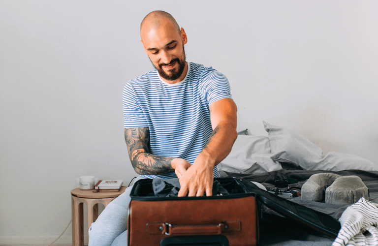 Time for holiday: a happy man packing his things up to set off on a journey.
