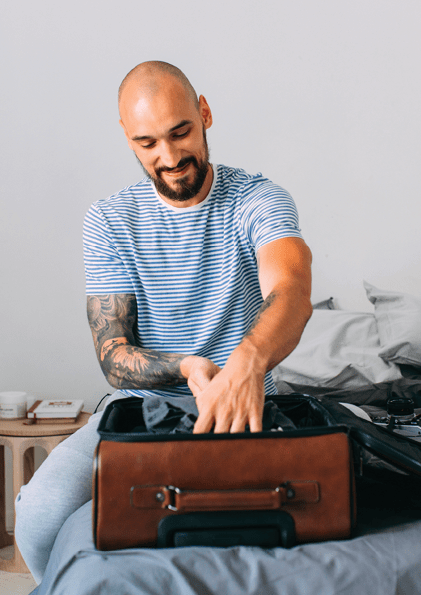 Time for holiday: a happy man packing his things up to set off on a journey.