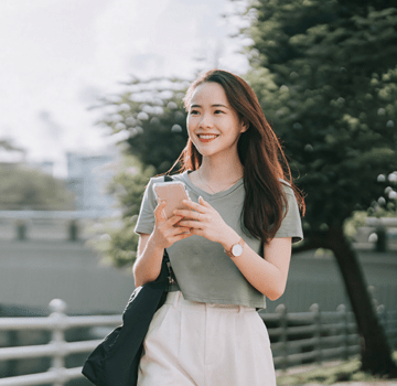 asian Chinese woman walking beside riverbank in the morning with smart phone