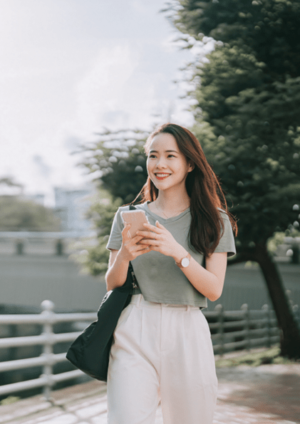 asian Chinese woman walking beside riverbank in the morning with smart phone