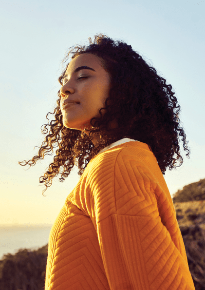 Freedom, relax and happy mindset of a woman from Brazil with sun on her face at a sea. Nature, ocean and beach water sunset with a young person feeling peace, wellness and gratitude from meditation