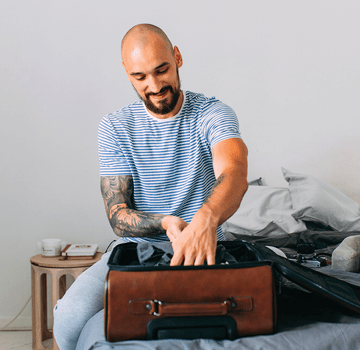 Time for holiday: a happy man packing his things up to set off on a journey.