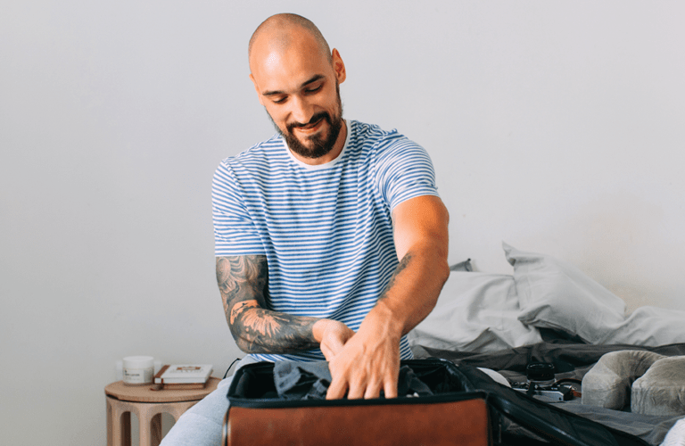 Time for holiday: a happy man packing his things up to set off on a journey.