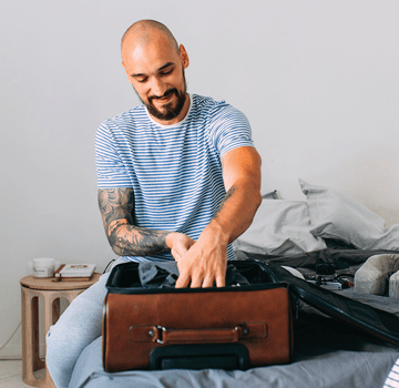 Time for holiday: a happy man packing his things up to set off on a journey.