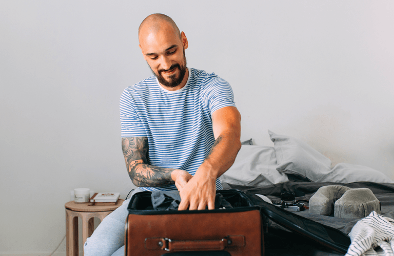 Time for holiday: a happy man packing his things up to set off on a journey.