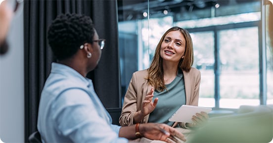 woman speaking with her colleague, both sitting