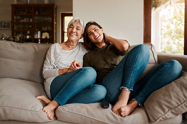 International Health Insurance. Two women enjoying each other's company as they sit together on a couch.