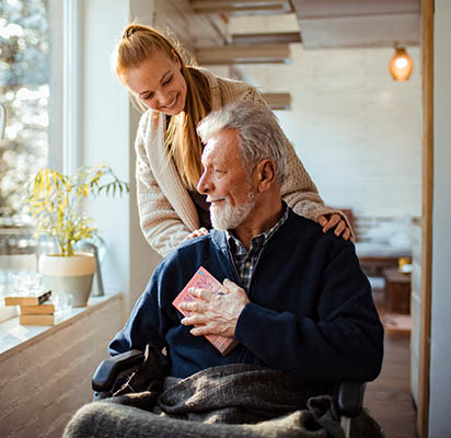 Critical illness Insurance. A woman assisting an elderly man in a wheelchair.