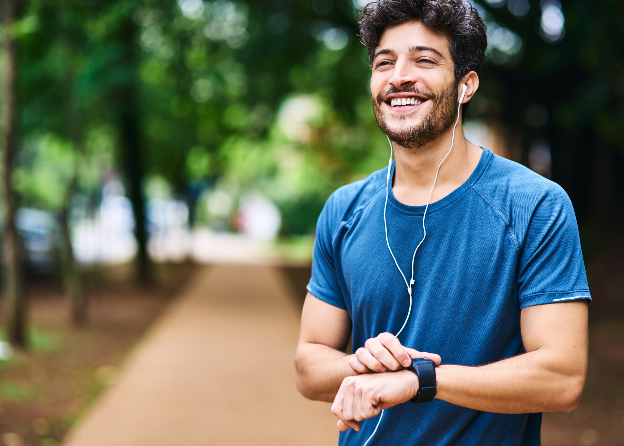 A sporty young man checking his fitness tracker while exercising outdoors