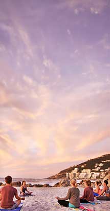 Group of people practicing yoga on a serene beach during a relaxing retreat, highlighting one of the recommended getaways to recharge the mind and body.