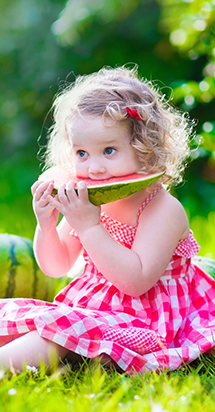 Small young girl eating watermelon to illustrate a nutritious and balanced diet.