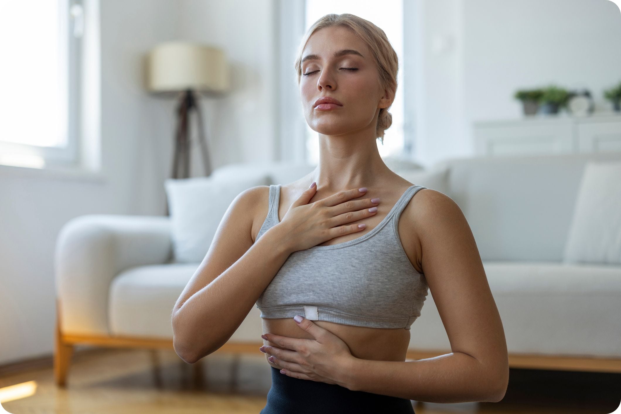 Woman practising mindful breathing at home with hands on chest and abdomen