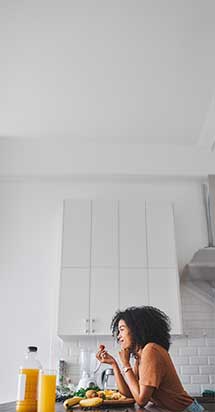 Young woman eating a healthy fruit snack at home, illustrating mindful eating habits as a way to manage stress and emotional eating