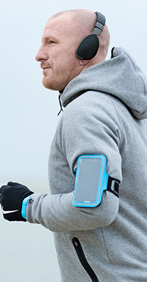 Middle-aged guy getting ready to exercise with his headphones on and mobile phone intact.