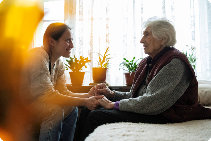 Female caretaker talking with senior woman.