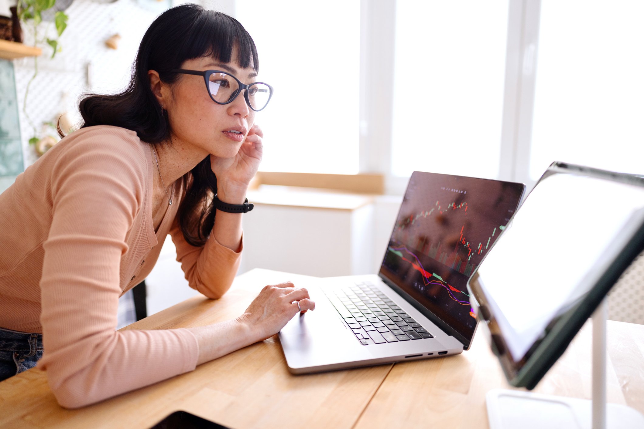 A woman working at a desk with two laptops, analysing data and interacting with AI tools.