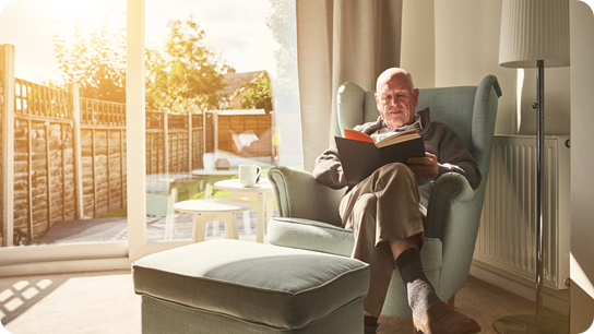 Old man sitting in arm chair, reading a book