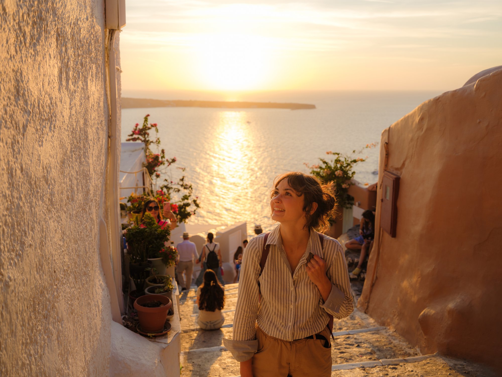 Woman walking the streets of Santorini at sunset, enjoying views of Oia village, Greece