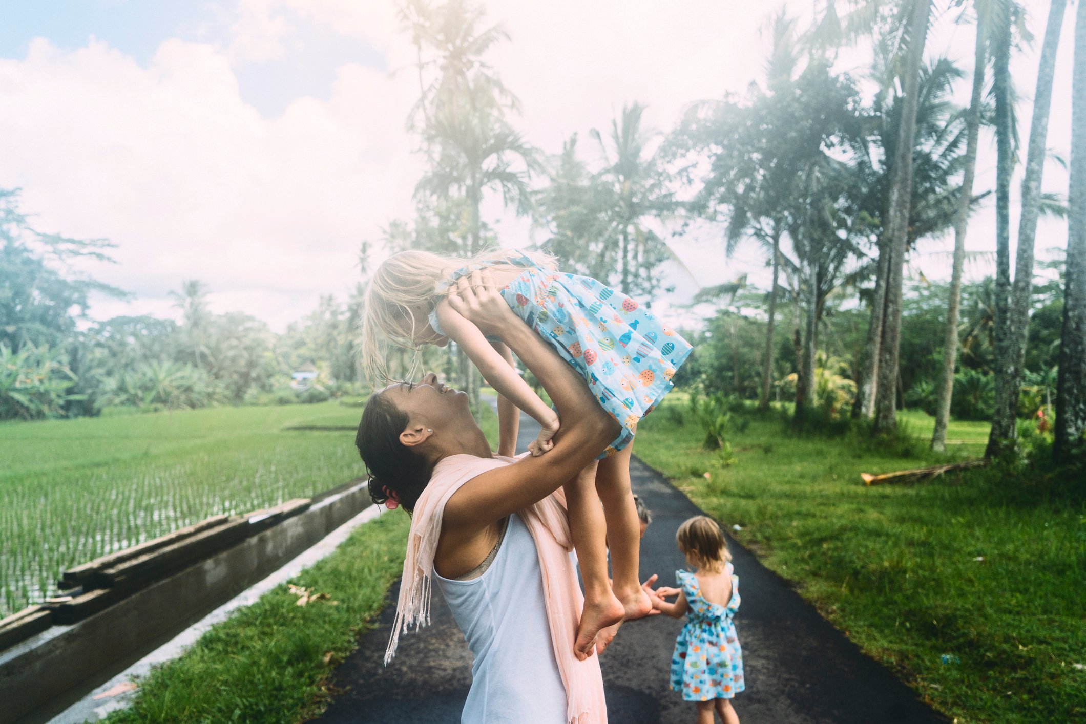 Expat mother holding her daughter near a waterfall in Bali, Indonesia