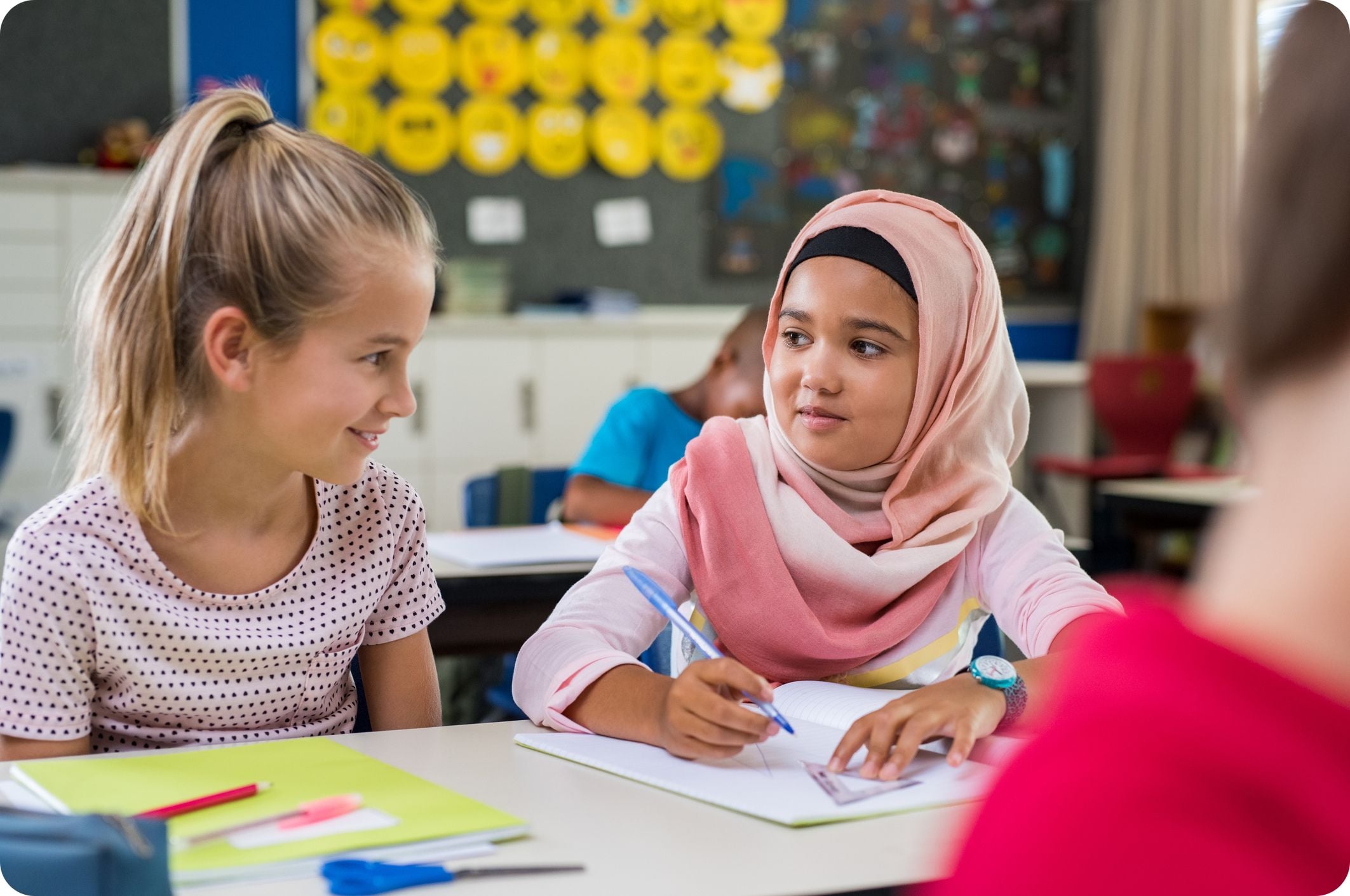 Two girls in a classroom sitting beside each other