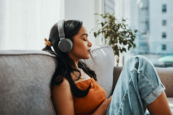 Woman relaxing listing to music on her headphones with her eyes closed.