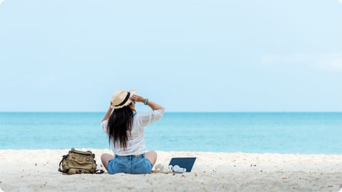 A woman on a beach facing the ocean 