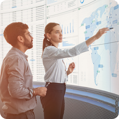 Male and female talking in front of a digital screen