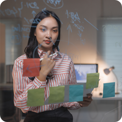 Businesswoman planning strategy on glass board with sticky notes