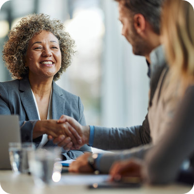 Happy insurance agent shaking hands with her customers in the office. 