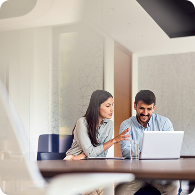 Two Young Businesspeople Working Together on a Laptop in a Modern Office