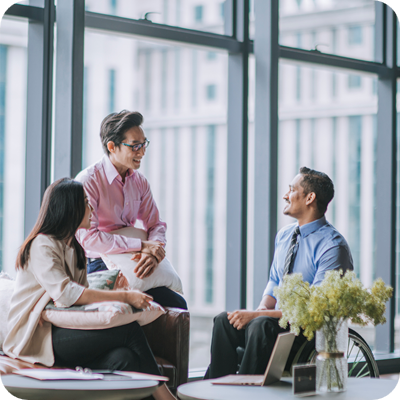 Indian male white collar worker in wheelchair discussion in office lounge with his colleague
