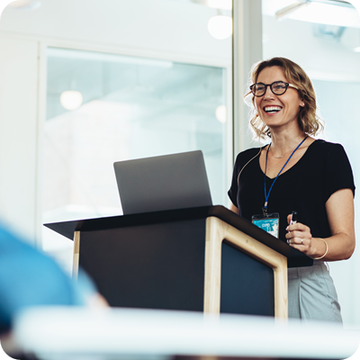 Businesswoman standing at podium with laptop giving a speech.
