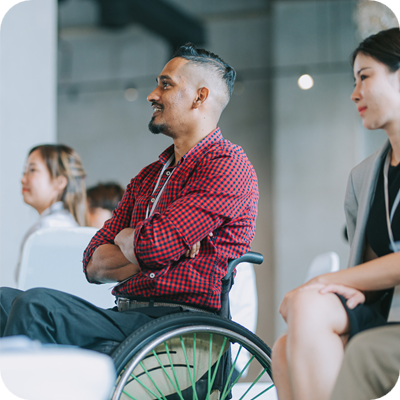 Asian Indian Disable man in wheelchair listening to presenter's speech on stage in business conference meeting