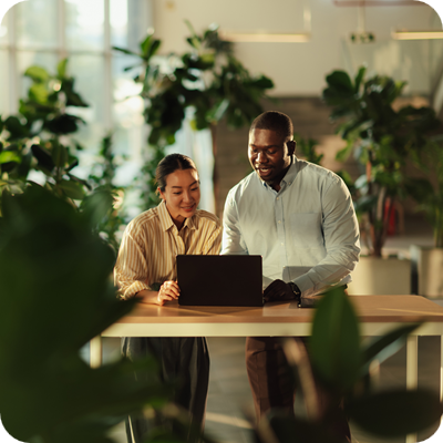 Business colleagues collaborating on laptop in green office space