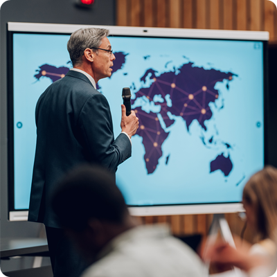 Man holding a speech, world map on screen