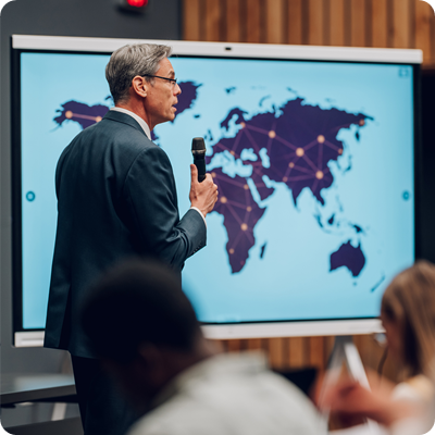 Man holding a speech, world map on screen