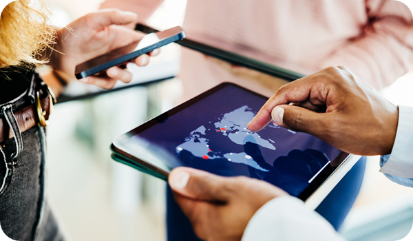 Business professionals collaborate using a digital tablet displaying a global map, indicating international reach and strategic planning.