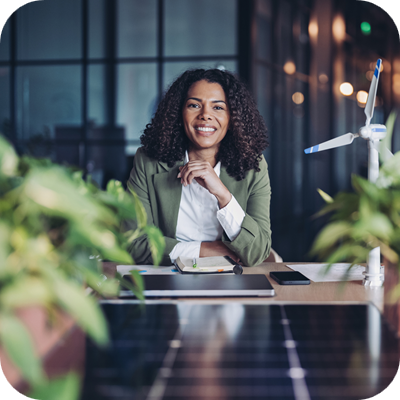 Woman at desk with small wind turbine and plants