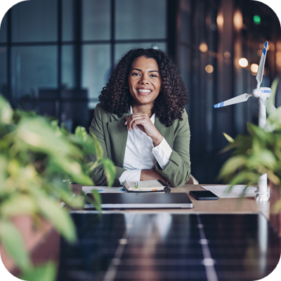 Woman at desk with small wind turbine and plants