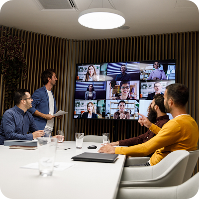 Low angle view of group of business people sitting around conference table and discussing project ideas with business partners via video call.