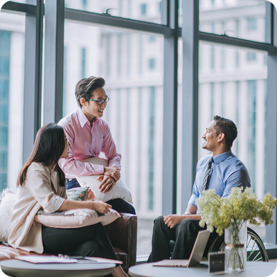 Indian male business man in wheelchair discussion in office lounge with his colleagues
