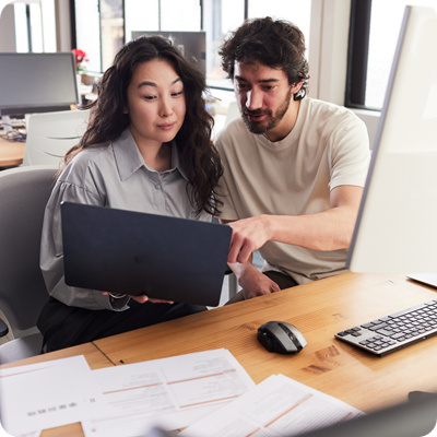 Two coworkers from a small business share a laptop during a meeting