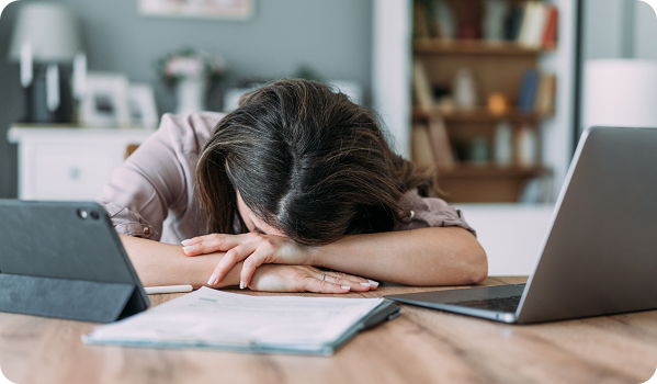 Stressed woman sitting on desk at home