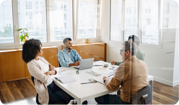 A team of four professionals are gathered around a white table in a modern office