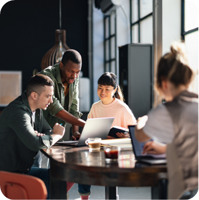 A dynamic team of young professionals is gathered around a table in the office, collaborating on their latest project
