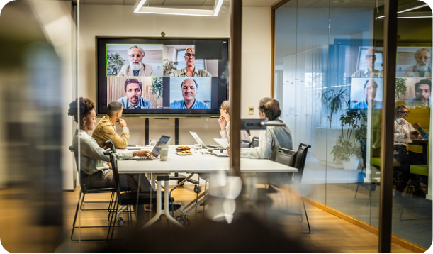 Group viewing video call screens and laptops at conference table