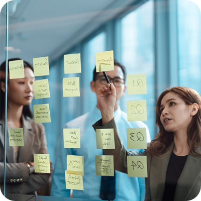 Business people brainstorming strategy and new ideas on glass wall with adhesive notes