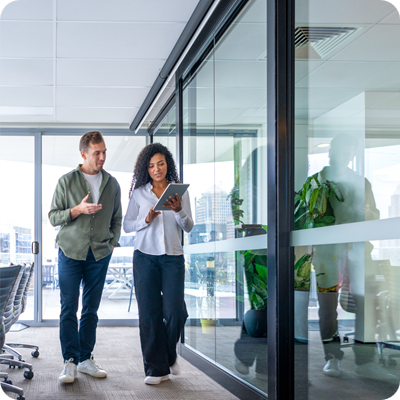 Man and woman walking and talking in the office brainstorming or discussing a project.