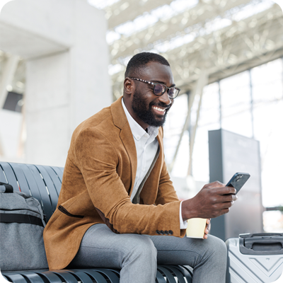 Smiling businessman using smart phone in station departure lounge